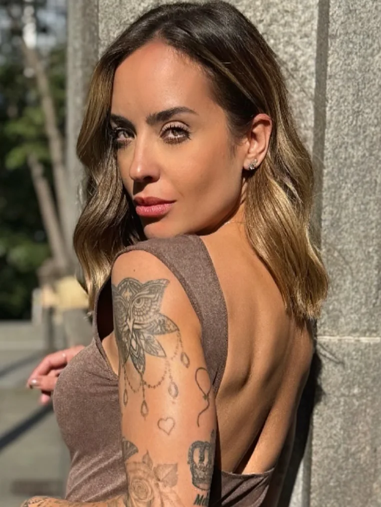 Julia Melo olhando por cima do ombro, com as costas tatuadas à mostra.