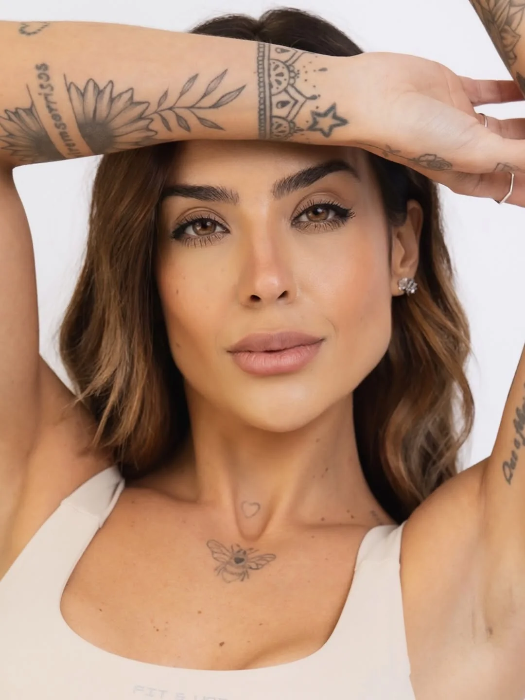 Retrato de perto de Julia Melo com o braço tatuado sobre a testa e olhar direto para a câmera.